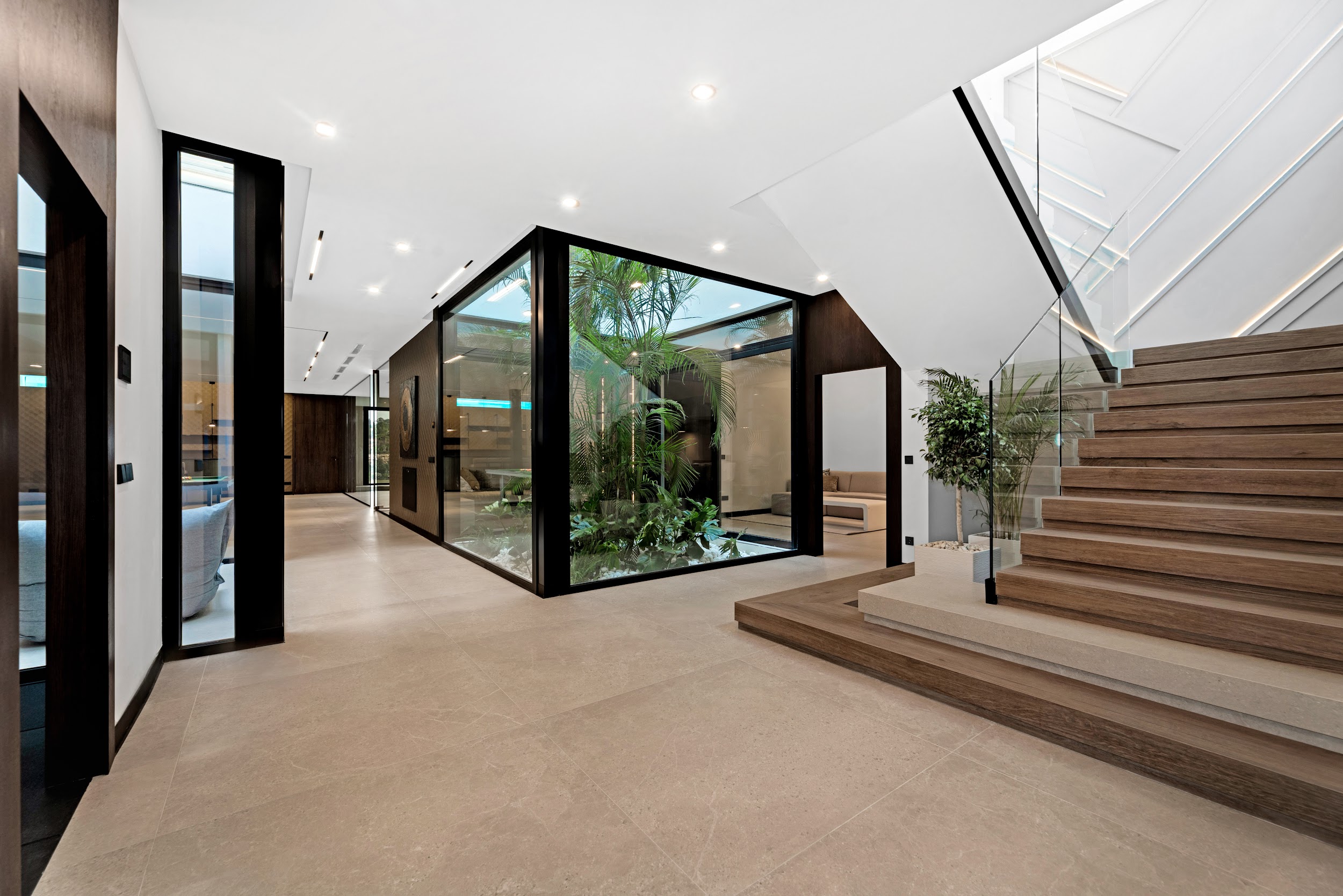 Hall con patio tropical y cristaleras en villa contemporánea