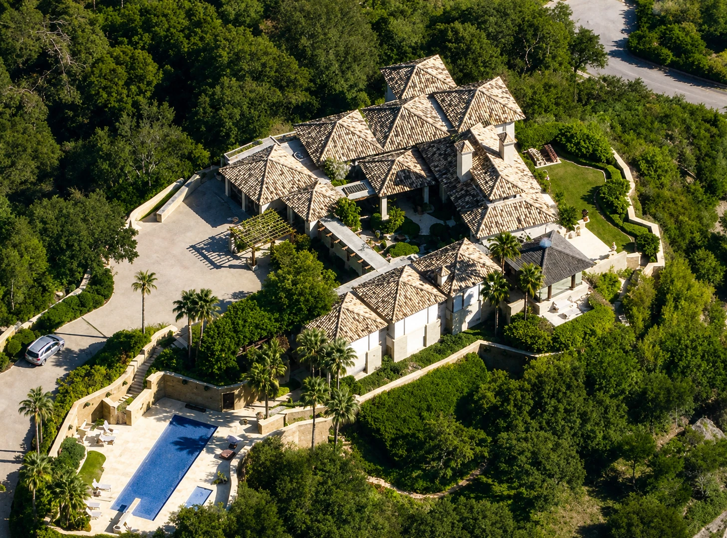 Vista aérea villa con cubierta de piedra natural y piscina en ladera arbolada, Costa del Sol