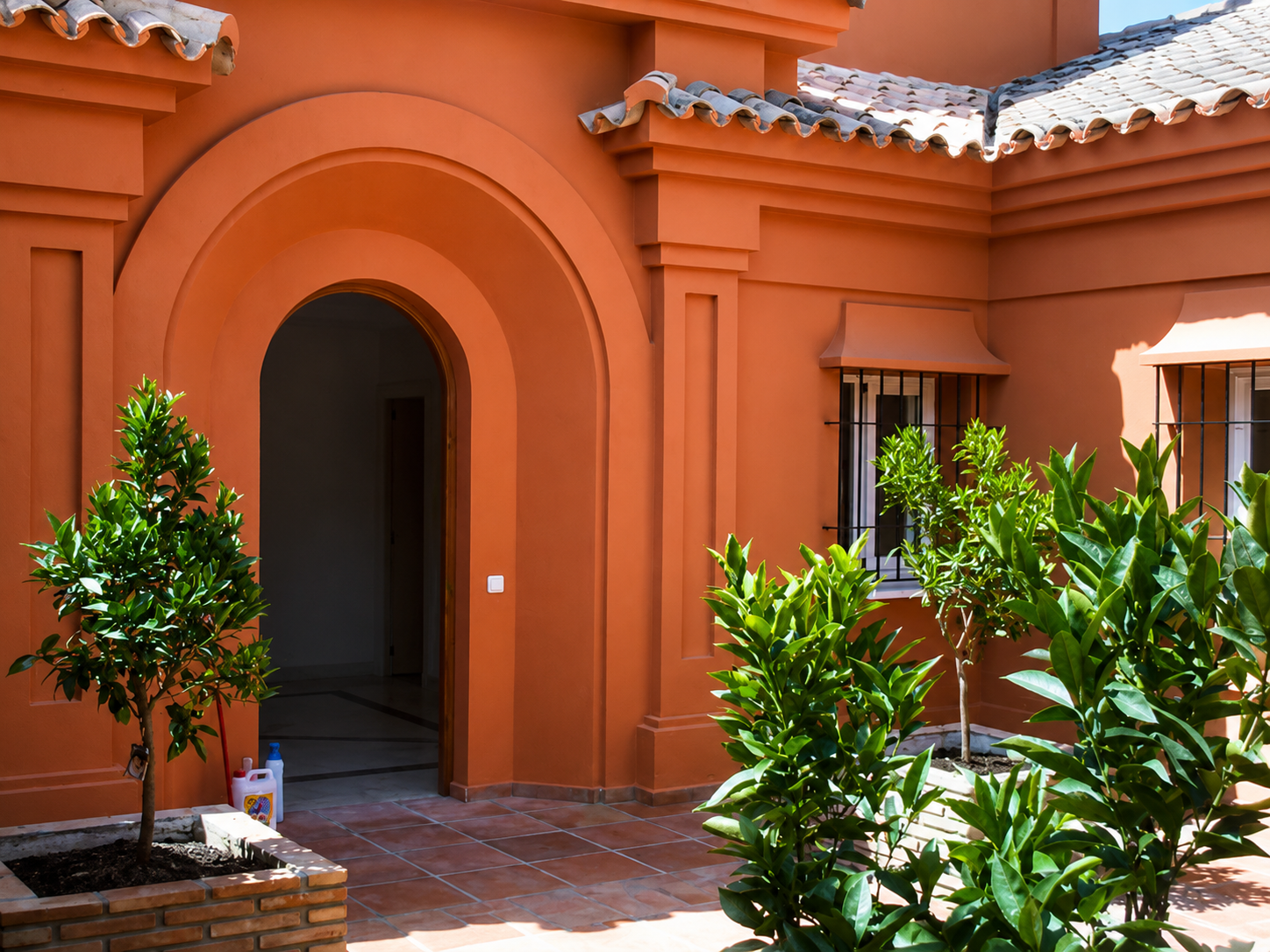 Patio andaluz terracota con arco y naranjos, villa Costa del Sol