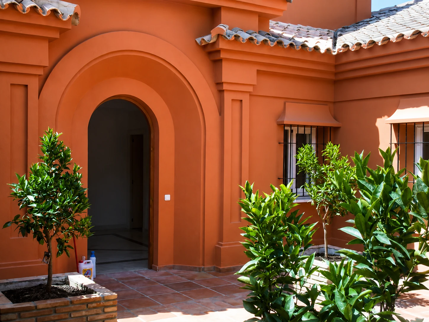 Patio andaluz terracota con arco y naranjos, villa Costa del Sol
