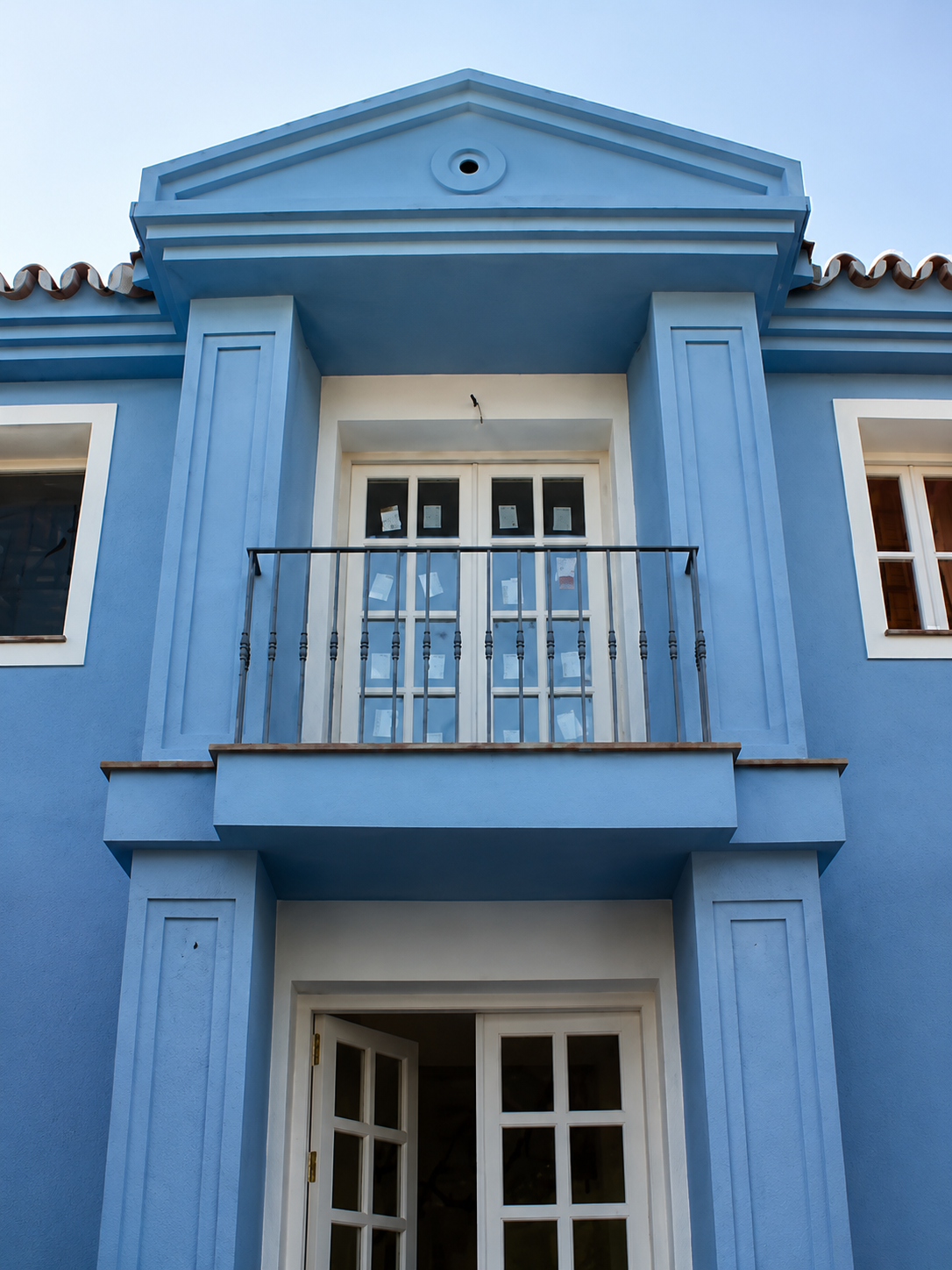 Detalle fachada azul celeste con frontón neoclásico, balcón y columnas, Costa del Sol