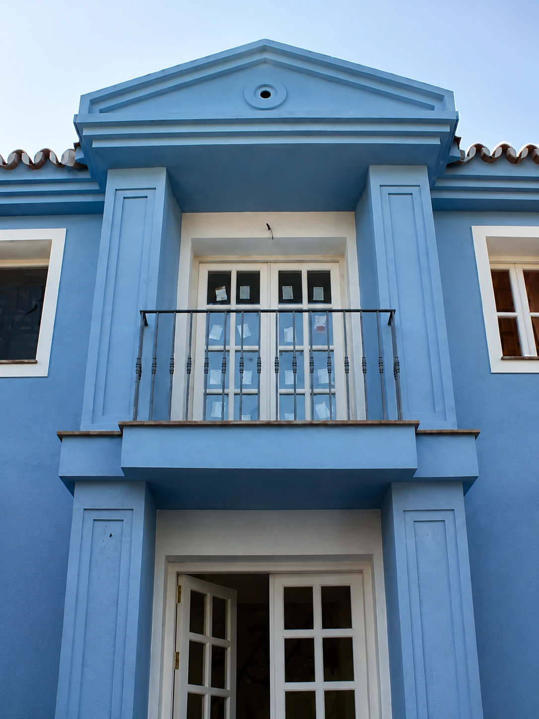 Detalle fachada azul celeste con frontón neoclásico, balcón y columnas, Costa del Sol