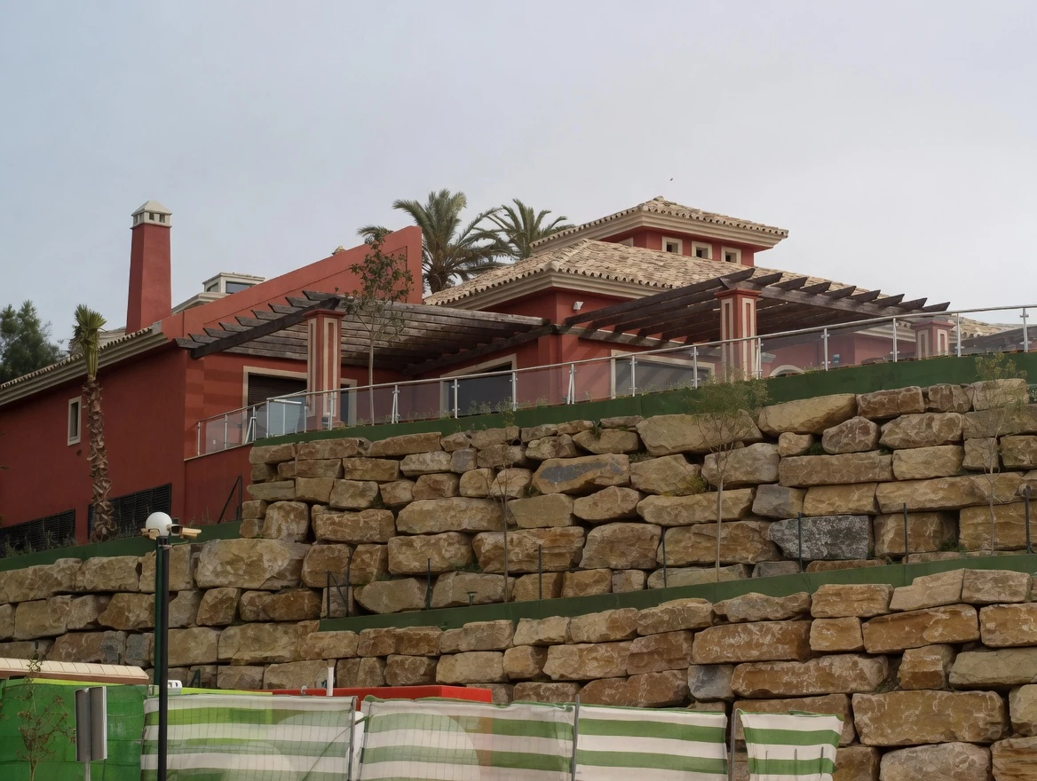 Villa roja en ladera con muro de mampostería de piedra, Costa del Sol Málaga