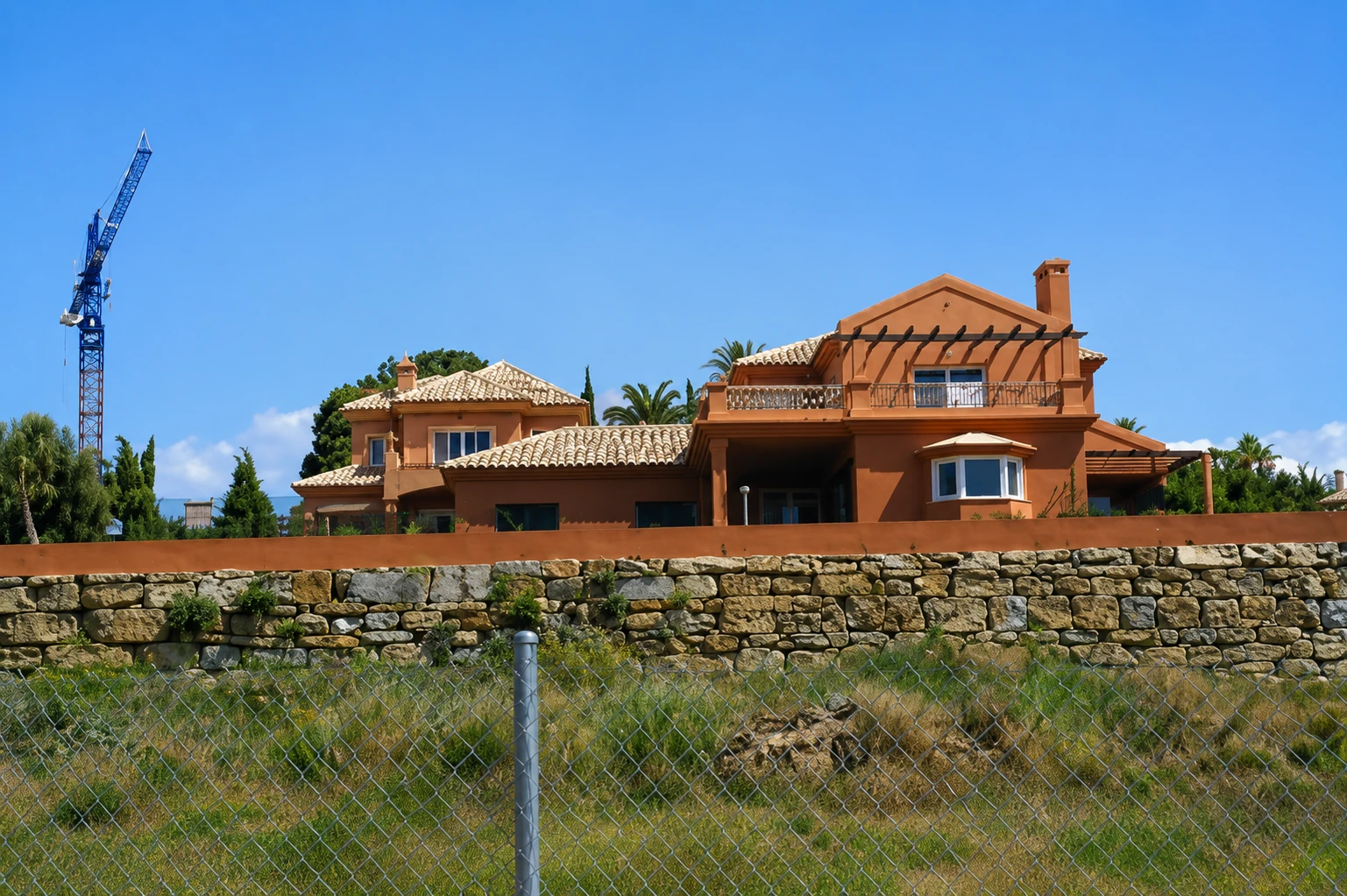 Villa terracota naranja en construcción con grúa, Costa del Sol Málaga