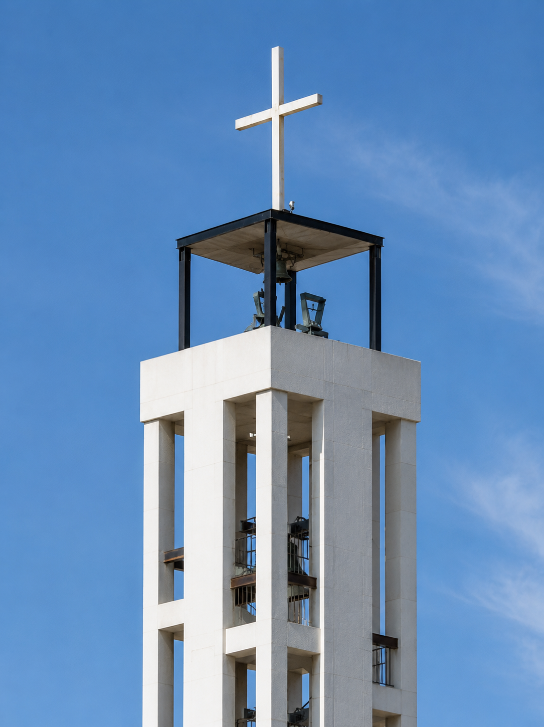 Detalle de la torre campanario de la Iglesia de la Asunción con cruz, campanas y estructura de hormigón blanco, Málaga
