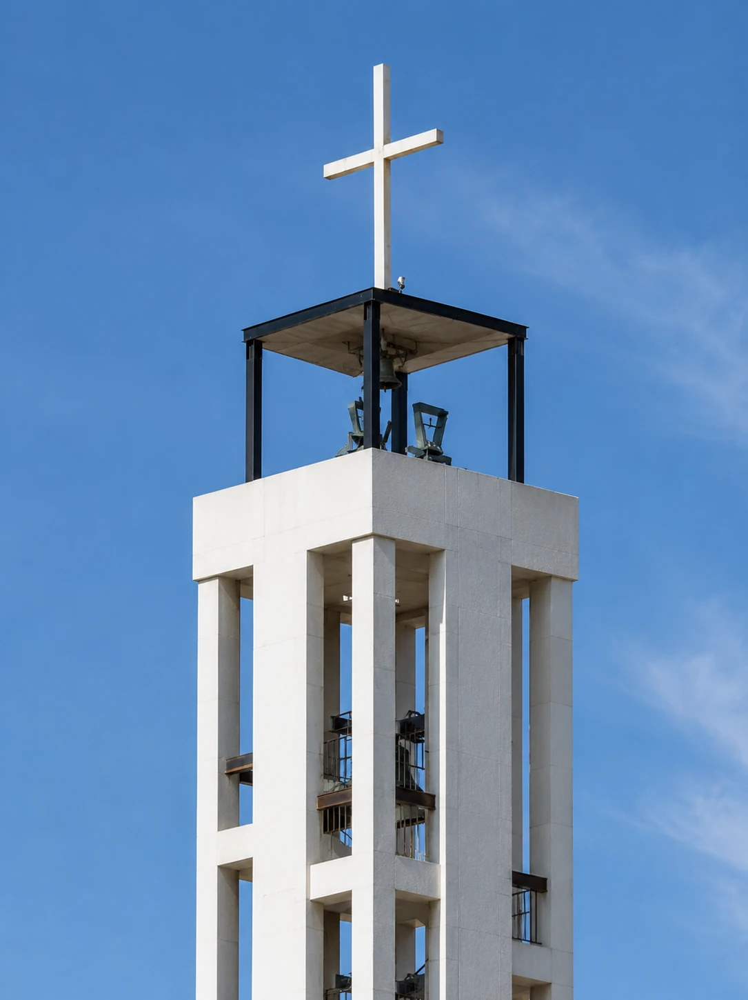 Detalle de la torre campanario de la Iglesia de la Asunción con cruz, campanas y estructura de hormigón blanco, Málaga